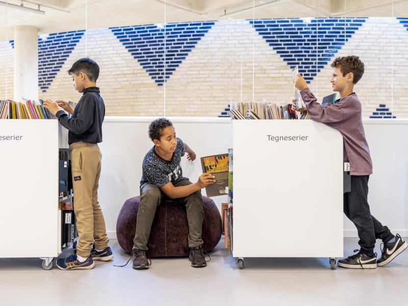 Tre drenge der kigger på tegneserier